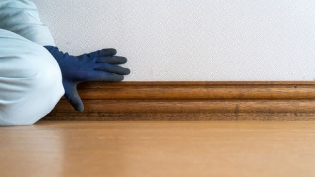 Ouvrier plaçant des plinthes en bois